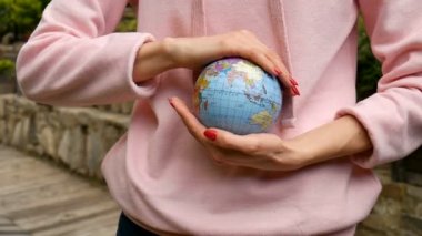 Kırmızı manikür ile pembe rahat kıyafetler genç kadın ergen elinde Ukraynalı Kiril harfleri geografical isimleri ile küçük bir dünya tutarak. Çevre sorumluluğu konsepti.