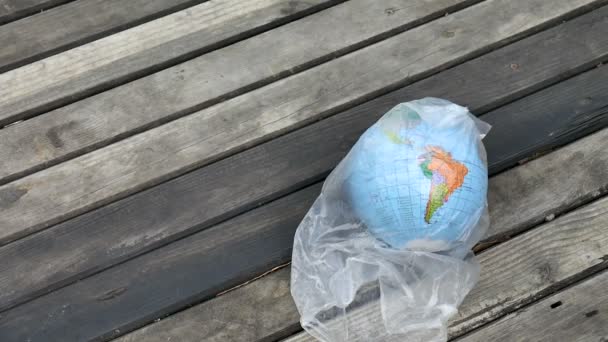 地球的顶视图,在木制背景的聚乙烯一次性包装上,以乌克兰西里尔字母的地理名称。塑料废物对环境的概念污染 — 图库视频影像