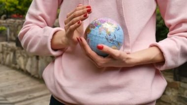 Kırmızı manikür ile pembe rahat kıyafetler genç kadın ergen elinde Ukraynalı Kiril harfleri geografical isimleri ile küçük bir dünya tutarak. Çevre sorumluluğu konsepti.