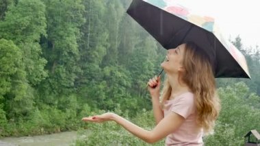 Bahar duş altında şemsiye ile mutlu güzel genç kadın. Kız pembe elbise giyiyor ve yağış zevk.