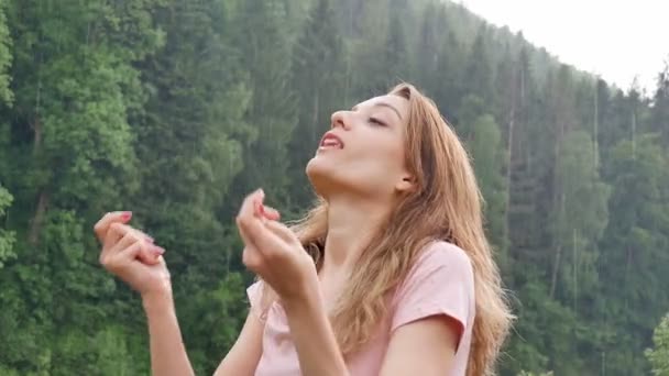 Szép boldog lány állt a nyári eső a háttérben a hegyek borított erdők. Fiatal nő boldogan örvény, és élvezi a meleg nyári eső — Stock videók