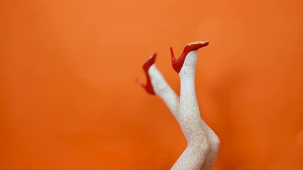 Женщина с длинными ногами, белые чулки в сетке на оранжевом фоне в студии. Ретро стиль — стоковое видео