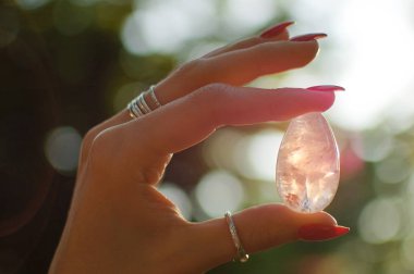 Vumfit, imbuilding veya meditasyon için şeffaf ametist kuvars yoni yumurta ile Kadın el. Gün doğumu arka planda açık havada ellerde parlayan kristal yumurta. Doğa kavramı ile kadın sağlığı ve birliği