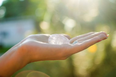 Vumfit, imbuilding veya meditasyon için şeffaf ametist kuvars yoni yumurta ile Kadın el. Gün doğumu arka plan açık ellerde parlayan kristal yumurta. Doğa kavramı ile kadın sağlığı ve birliği