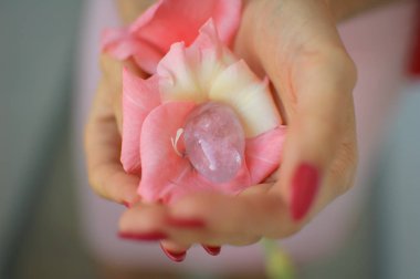 Pembe gladiolus çiçek içinde vumbuilding için şeffaf ametist yoni yumurta ile kadın el in fotoğraf kadar yakın. Elinde kuvars kristalüst görünümü. Kadın sağlığı kavramı