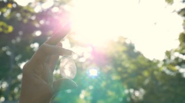 Vumfit, imbuilding veya meditasyon için şeffaf ametist kuvars yoni yumurta ile Kadın el. Gökyüzü ve gündoğumu arka plan açık havada ellerde parlayan kristal yumurta. Kadın sağlığı kavramı.