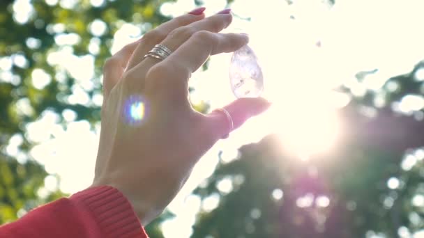 Frauenhand mit transparentem Amethyst-Quarz-Yoni-Ei für Vumfit, Imbuilding oder Meditation. leuchtende Kristall-Ei in den Händen am Himmel und Sonnenaufgang Hintergrund im Freien. Frauengesundheitskonzept. — Stockvideo
