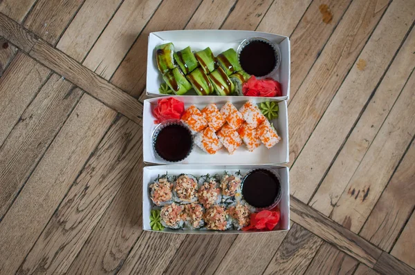 Japanese cuisine. Sushi set on a carton box over wooden background. Food for take away or sushi delivery concept