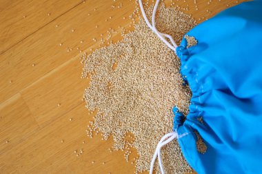 Ahşap arka plan üzerinde mavi yeniden kullanılabilir paket beyaz Quinoa tohumları. Kopyalama alanı