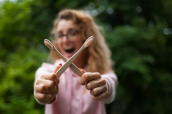 Junges schönes Mädchen hält eine nützliche Bambuszahnbürste in der Hand und lächelt in die Kamera. Umweltfreundlichkeit und Null-Abfall-Konzept. — Stockfoto