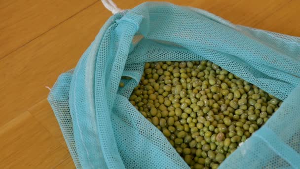 Close up of green mung bean vigna radiata in blue reusable package on wooden background. Conceito de embalagem ecológica — Vídeo de Stock