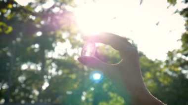 Vumfit, imbuilding veya meditasyon için şeffaf ametist kuvars yoni yumurta ile Kadın el. Gökyüzü ve gündoğumu arka plan açık havada ellerde parlayan kristal yumurta. Kadın sağlığı kavramı.