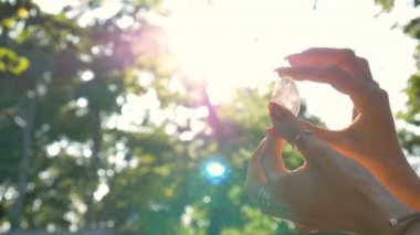 Vumfit, imbuilding veya meditasyon için şeffaf ametist kuvars yoni yumurta ile Kadın el. Gökyüzü ve gündoğumu arka plan açık havada ellerde parlayan kristal yumurta. Kadın sağlığı kavramı.