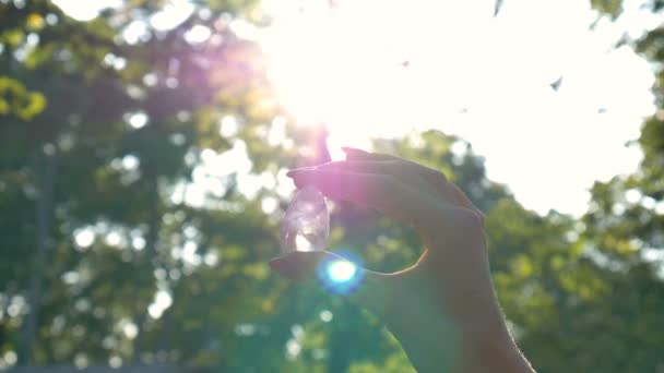 Frauenhand mit transparentem Amethyst-Quarz-Yoni-Ei für Vumfit, Imbuilding oder Meditation. leuchtende Kristall-Ei in den Händen am Himmel und Sonnenaufgang Hintergrund im Freien. Frauengesundheitskonzept. — Stockvideo