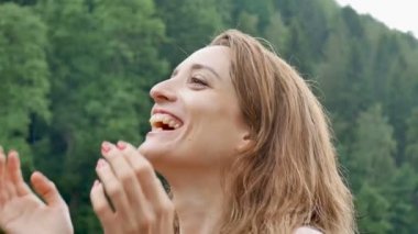 Portreyi kapat. Dağlarda mutlu bir kıvırcık kız şemsiye olmadan yaz yağmuru sahiptir. Kız mutlu ve neşeyle gülüyor. doğanın güzelliği