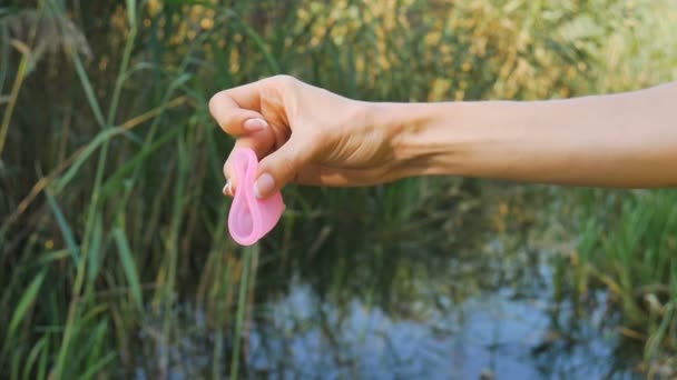 Göl ile yeşil doğal arka plan üzerinde kadın ellerde Pembe silikon adet fincan. Kadın sağlığı kavramı, sıfır atık alternatifleri