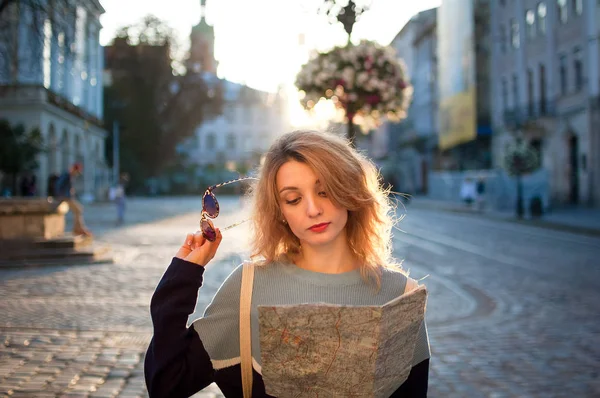 Kvinnan går förlorad i gamla europeiska staden titta på en karta och söka efter riktning tidigt på morgonen på tomma gamla torget — Stockfoto