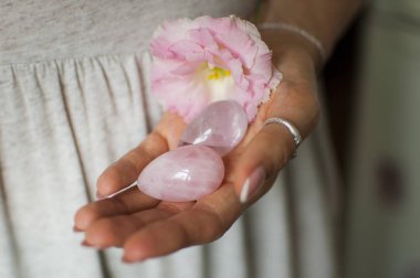 Vumfit, imbuilding veya meditasyon için iki yoni yumurta tutan kadın eller pembe kuvars ve beyaz çiçekler kapalı şeffaf menekşe ametist yapılır