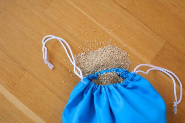 Ahşap arka plan üzerinde mavi yeniden kullanılabilir paket beyaz Quinoa tohumları üst görünümü. Sağlıklı beslenme konsepti