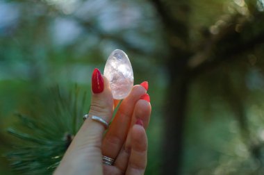 Vumfit, imbuilding veya meditasyon için şeffaf ametist kuvars yoni yumurta ile Kadın el. Gökyüzü ve gündoğumu arka plan açık havada ellerde parlayan kristal yumurta. Kadın sağlığı kavramı.