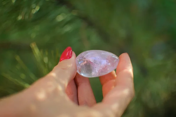 Mano femenina con huevo de cuarzo amatista transparente yoni para vumfit, imbuilding o meditación. Huevo de cristal brillante en las manos en el cielo y el fondo del amanecer al aire libre. Concepto de salud para mujeres . — Foto de Stock