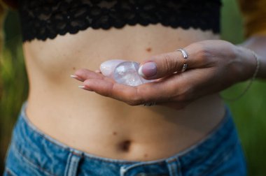 Vumfit, imbuilding veya meditasyon için iki yoni yumurtası tutan kadın eller çıplak karnının üzerinde pembe kuvarstan ve şeffaf mor ametistten yapılır.