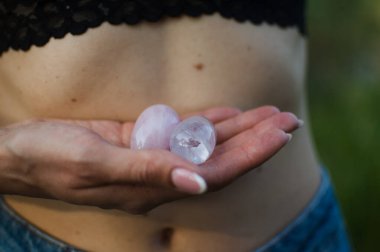 Vumfit, imbuilding veya meditasyon için iki yoni yumurtası tutan kadın eller çıplak karnının üzerinde pembe kuvarstan ve şeffaf mor ametistten yapılır.
