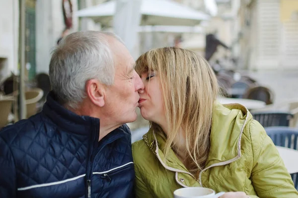 Hombre mayor guapo está abrazando a su joven esposa rubia pasar tiempo juntos al aire libre en la ciudad antigua durante principios de primavera u otoño . —  Fotos de Stock