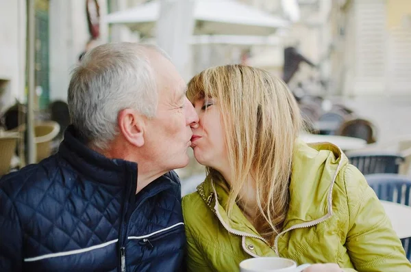 Retrato de pareja romántica feliz con diferencia de edad besándose al aire libre en la ciudad antigua durante principios de primavera u otoño —  Fotos de Stock