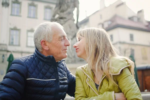 Retrato de pareja romántica feliz con diferencia de edad besándose al aire libre en la ciudad antigua durante principios de primavera u otoño —  Fotos de Stock