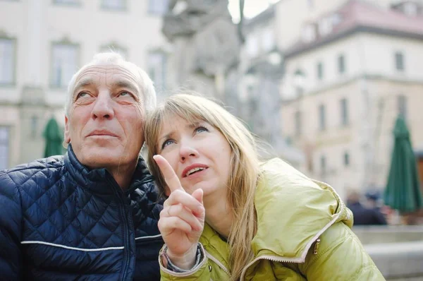 Retrato al aire libre del anciano y su joven esposa rubia pasando tiempo juntos en la antigua ciudad a principios de primavera u otoño. Pareja con diferencia de edad apuntando a algún lugar turístico —  Fotos de Stock