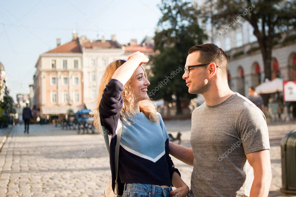 Young tourists couple discussing something in an ancient European city early in the morning on empty square, travelling problems concept