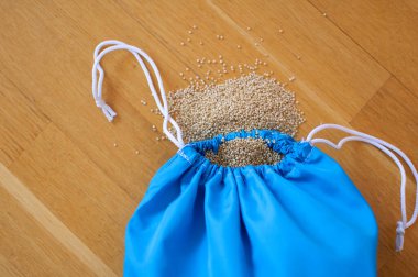 Ahşap arka plan üzerinde şeffaf mavi yeniden kullanılabilir çanta beyaz Quinoa tohumları. Vejetaryen gıda kavramı