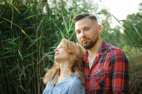 Primer plano retrato de pareja joven abrazando y mirando a la cámara en el fondo tallos verdes, hipsters concepto — Foto de Stock