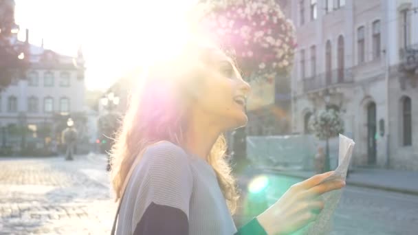 Feliz chica adulta emocionada está mirando el mapa de papel y en busca de dirección temprano en la mañana en la antigua ciudad europea en la plaza vacía — Vídeos de Stock