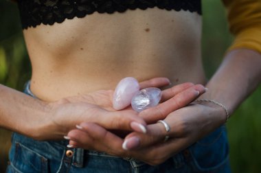 Vumfit, imbuilding veya meditasyon için iki yoni yumurtası tutan kadın eller çıplak karnının üzerinde pembe kuvarstan ve şeffaf mor ametistten yapılır.