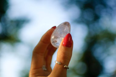 Vumfit, imbuilding veya meditasyon için şeffaf ametist kuvars yoni yumurta ile Kadın el. Gökyüzü ve gündoğumu arka plan açık havada ellerde parlayan kristal yumurta. Kadın sağlığı kavramı.
