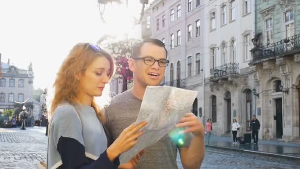 Ungt par tittar på Stadskartan och letar efter riktning tidigt på morgonen på tomma gamla torg någonstans i Europa, resekoncept — Stockvideo