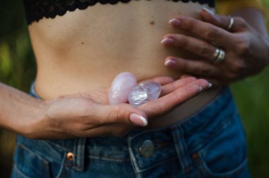 Vumfit, imbuilding veya meditasyon için iki yoni yumurtası tutan kadın eller çıplak karnının üzerinde pembe kuvarstan ve şeffaf mor ametistten yapılır.