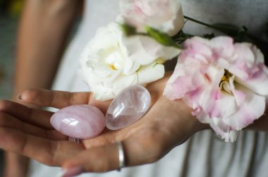 Vumfit, imbuilding veya meditasyon için iki yoni yumurta tutan kadın eller pembe kuvars ve beyaz çiçekler kapalı şeffaf menekşe ametist yapılır