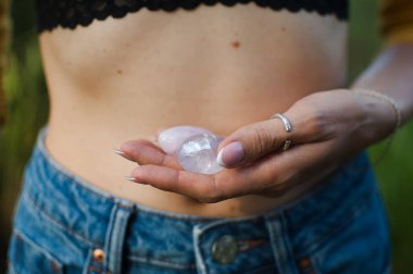 Vumfit, imbuilding veya meditasyon için iki yoni yumurtası tutan kadın eller çıplak karnının üzerinde pembe kuvarstan ve şeffaf mor ametistten yapılır.