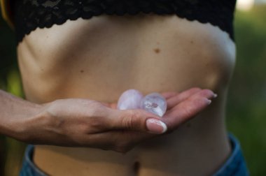 Vumfit, imbuilding veya meditasyon için iki yoni yumurtası tutan kadın eller çıplak karnının üzerinde pembe kuvarstan ve şeffaf mor ametistten yapılır.