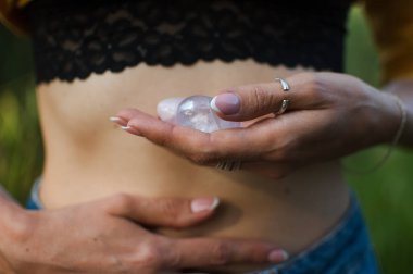 Vumfit, imbuilding veya meditasyon için iki yoni yumurtası tutan kadın eller çıplak karnının üzerinde pembe kuvarstan ve şeffaf mor ametistten yapılır.