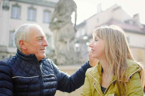 Hombre mayor guapo está abrazando a su joven esposa rubia pasar tiempo juntos al aire libre en la ciudad antigua durante principios de primavera u otoño . —  Fotos de Stock