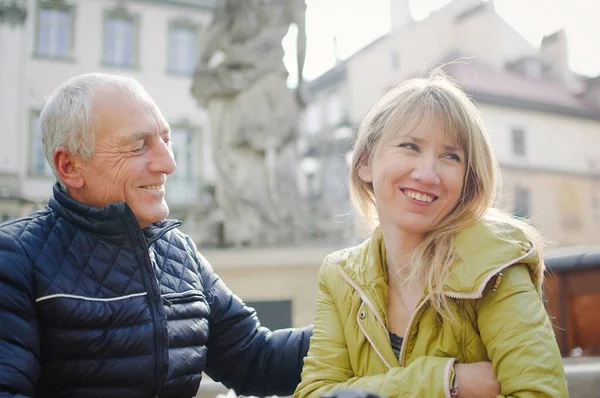 Hombre mayor guapo está abrazando a su joven esposa rubia pasar tiempo juntos al aire libre en la ciudad antigua durante principios de primavera u otoño . —  Fotos de Stock