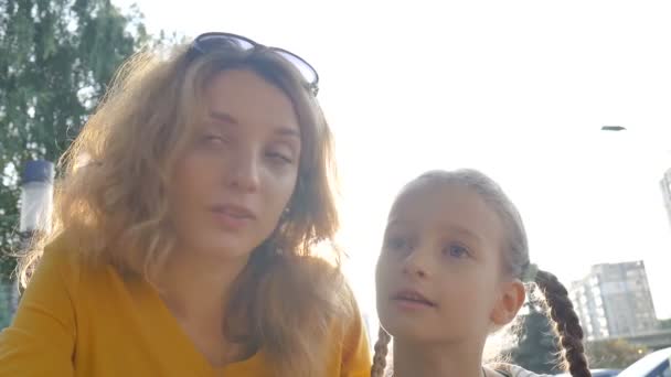 Çekici genç anne, küçük kızıyla birlikte sabahın erken saatlerinde dışarıda bir yerlerde mutlu bir aile kavramı hakkında konuşuyor. — Stok video