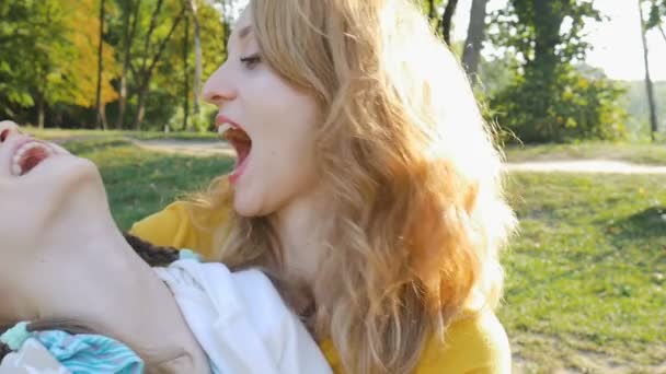 Vista de cerca de la madre en camisa amarilla y su hija niña jugando y abrazándose. Feliz fin de semana familiar en el parque durante la primavera u otoño . — Vídeo de stock