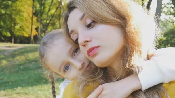 Primer plano retrato de belleza mujer de otoño en camisa de estilo amarillo con su hija pequeña en ropa azul pasar tiempo en el parque durante el fin de semana familiar. Concepto de maternidad feliz — Vídeos de Stock