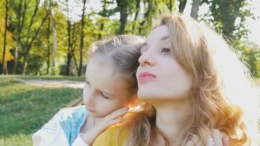 Sarı renkli tişörtlü güzel bir sonbahar kadını portresi ve mavi elbiseli küçük kızı aile hafta sonu boyunca parkta vakit geçiriyorlar. Mutlu annelik kavramı