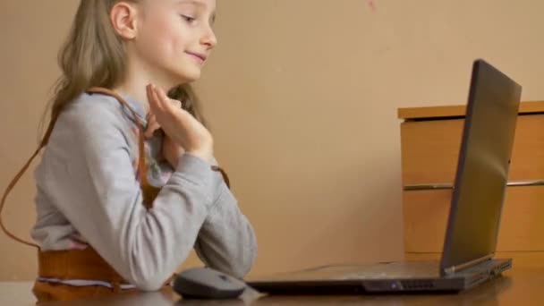 Μικρή μαθήτρια σπουδάζει στο σπίτι με τη δασκάλα της χρησιμοποιώντας βίντεο chat στο μαύρο laptop της λόγω της αυτο-απομόνωσης λόγω της πανδημίας του Coronavirus Covid-19 — Αρχείο Βίντεο